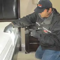 Bed bug inspection technician checking a mattress and bed frame for signs of infestation in Birmingham, AL