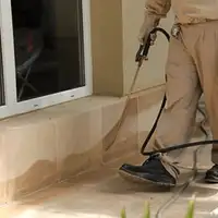 General pest control technician spraying exterior perimeter around a home in Birmingham, AL