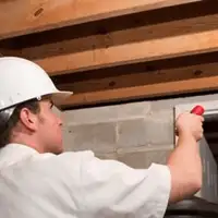 Termite inspection technician checking a basement wall and framing for termite activity in Birmingham, AL